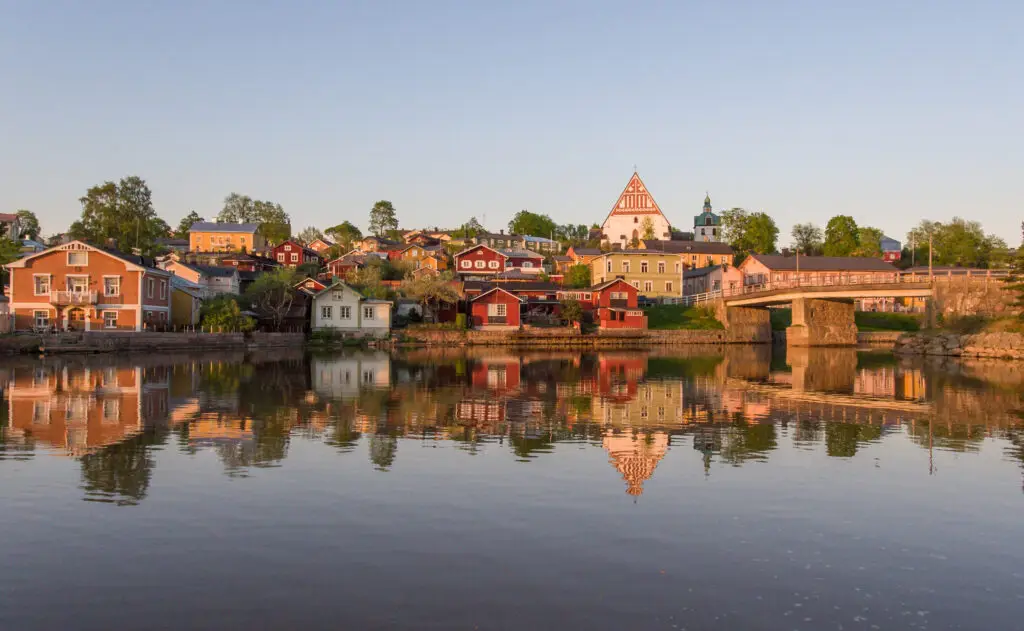 Sunset view of the Porvoo River with colorful houses and the old bridge, reflecting in the calm water in Porvoo, Finland.