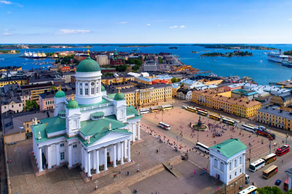 Aerial view of Helsinki's Senate Square featuring the Helsinki Lutheran Cathedral, with the bustling cityscape and Baltic sea in the background, illustrating a popular Finnish tourist destination.