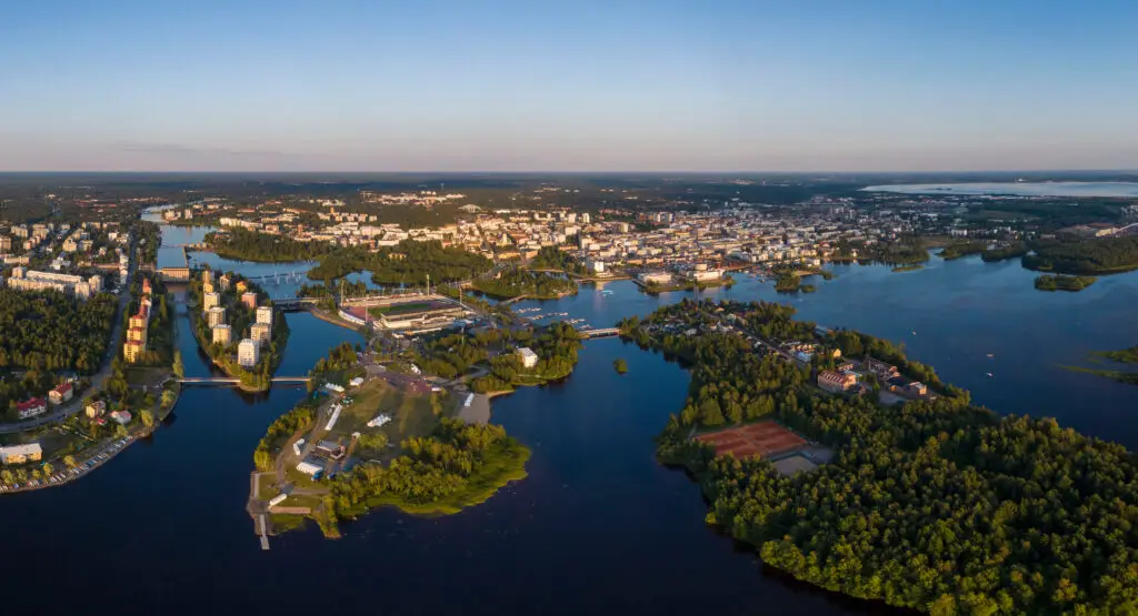 Aerial view of Oulu, Finland showcasing the picturesque cityscape with rivers, lush greenery, and modern architecture during sunset, enhancing Scandinavian tourism attractions.